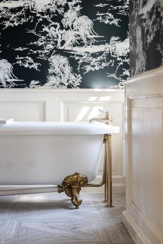 a bathroom with a white tub and a black and white wallpaper at The Bentley Suite in Gileston