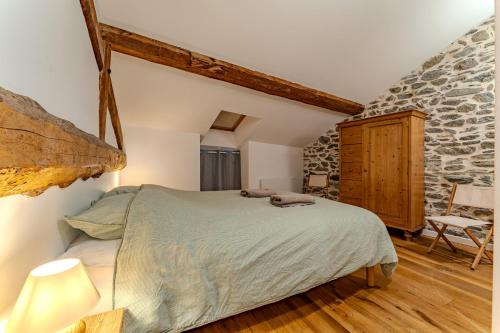 a bedroom with a bed and a stone wall at Chalet des Granges in Saint-Marcel