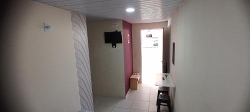 een hal met een deur en een televisie aan een muur bij Suites Pico do Cristal in Caparaó Velho