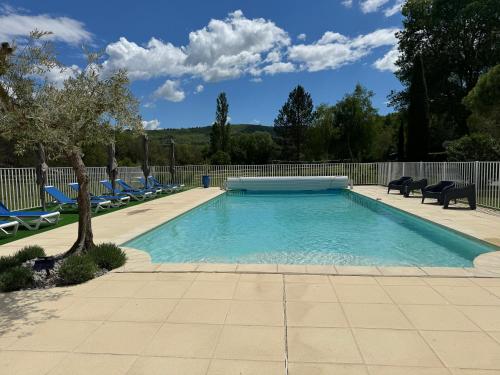 une piscine avec des chaises bleues et une clôture dans l'établissement Chambre d'hôtes Zephyr Libeccio Le Moulin de Prédelles, à Reillanne