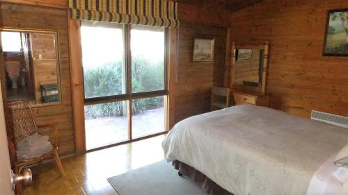 a bedroom with a bed and a large window at Gunyah Valley Retreat in Goornong