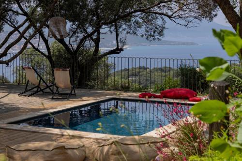 a swimming pool with two chairs and a fence at Résidence Licciola in Propriano