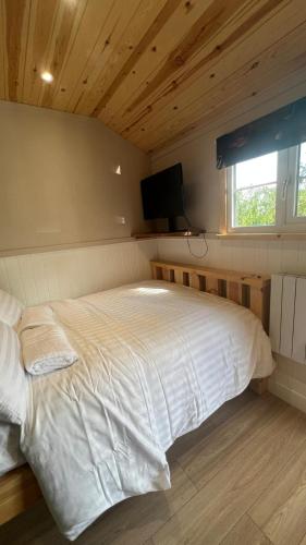 Schlafzimmer mit einem großen weißen Bett und einem Flachbild-TV in der Unterkunft The Rodney Shepards hut in Eyam