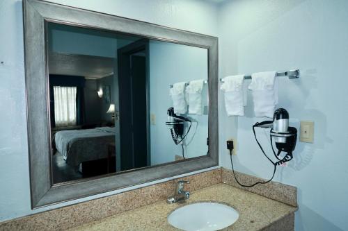 a bathroom with a mirror and a sink and a bed at Quarters Inn & Suites in Antioch