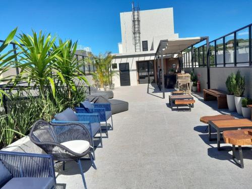 eine Terrasse mit blauen Stühlen und Tischen an einem Gebäude in der Unterkunft Estudio Aurea Bauten 210 in Tambaú