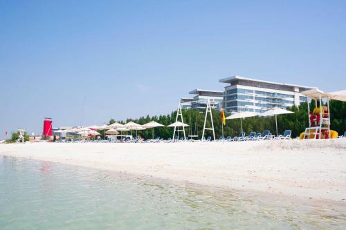 a beach with chairs and umbrellas and a building at Yas Island Mayan 2 Junior 1 Bed with Private Beach Access by Central Stay in Abu Dhabi