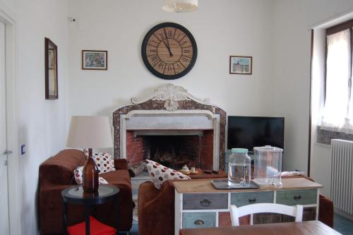 a living room with a fireplace and a clock on the wall at Villa Nini' Exclusive Nature by ElodeaGroup in Pellezzano