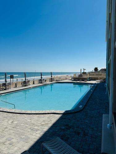 a large swimming pool next to the beach at Daytona Inn Beach Resort Step Outside and Put Your Feet in the Sand Beach Vibes in Daytona Beach