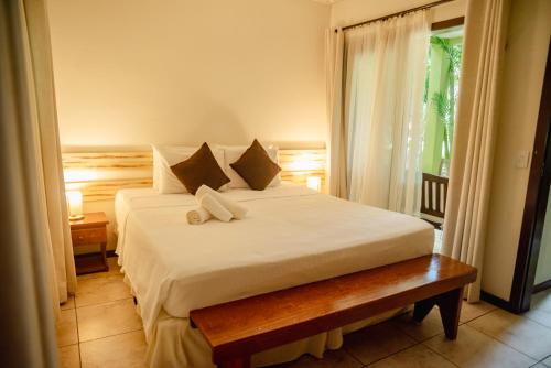 a bedroom with a large white bed and a window at Recanto da Mata Pipa in Pipa