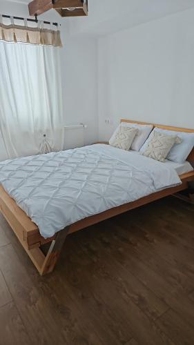 a bed in a bedroom with a white curtain at Cabana Stil in Mărişel