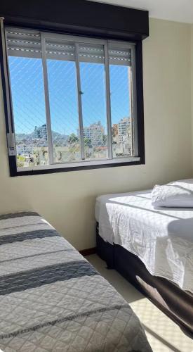 a bedroom with two beds and a large window at Apto aconchegante, central, prox ao carrefour in Santa Maria