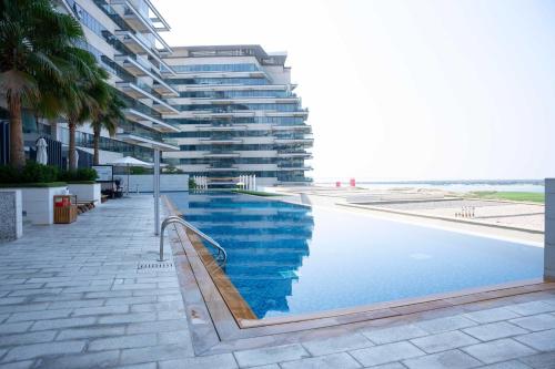 a large building with a swimming pool next to a beach at Yas Island Mayan 2 Junior 1 Bed with Private Beach Access by Central Stay in Abu Dhabi