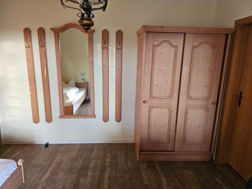 a bedroom with a wooden cabinet and a mirror at Braukeller Fattigau in Oberkotzau
