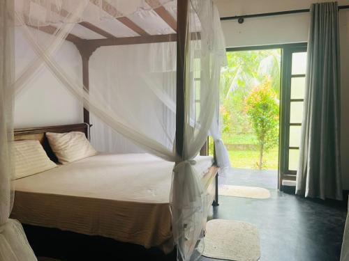 a bedroom with a canopy bed with a window at Mashi's Villa in Sigiriya