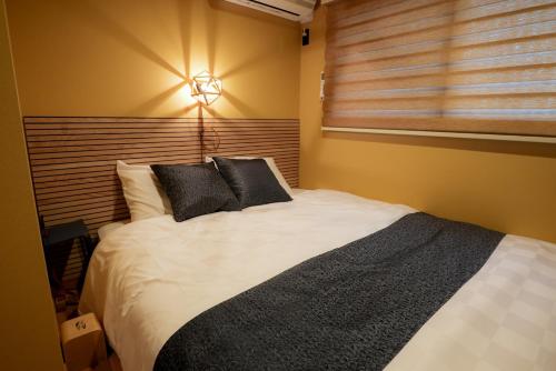 a bedroom with a bed with black pillows and a window at Tabiudo Stay Miyajima 01-02 - Vacation STAY 20513 in Fukae