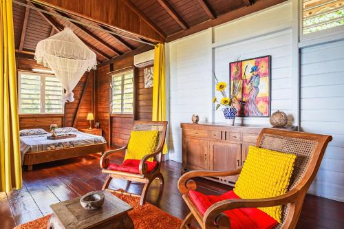 Una sala de estar con dos sillas y una cama. en Villasticreole, en Deshaies