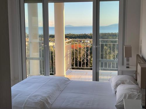 ein Schlafzimmer mit einem weißen Bett und einem großen Fenster in der Unterkunft Villa Evangelia in Karavádhos