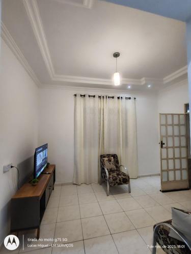 a living room with a tv and a chair at LM Home 1 - casa com 2 quartos in Governador Valadares
