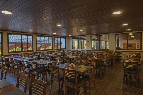 uma sala de jantar com mesas, cadeiras e janelas em Vila Dom Bosco em Campos de Jordão