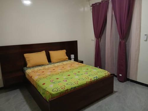 a bed in a bedroom with purple curtains at Villa Standing Ngaparou in Ngaparou