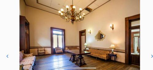 a living room with a table and a chandelier at posada el obispado in Querétaro
