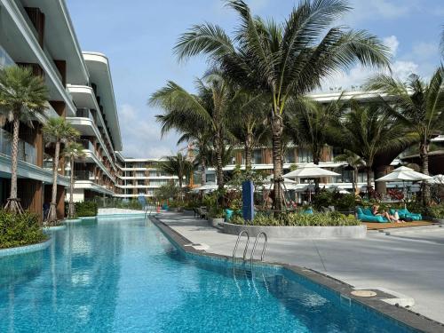 une piscine avec des palmiers et un bâtiment dans l'établissement The Sunshine Beach Family Suite with Pool, à Layan Beach