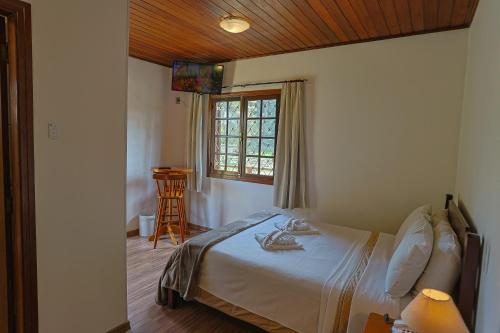 a bedroom with a bed and a window and a chair at Vila Dom Bosco in Campos do Jordão