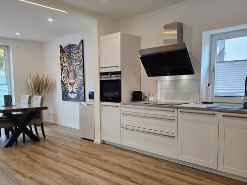 a kitchen with white cabinets and a table and a painting at FeWo Safari - zwischen Holstentor & Ostsee in Lübeck