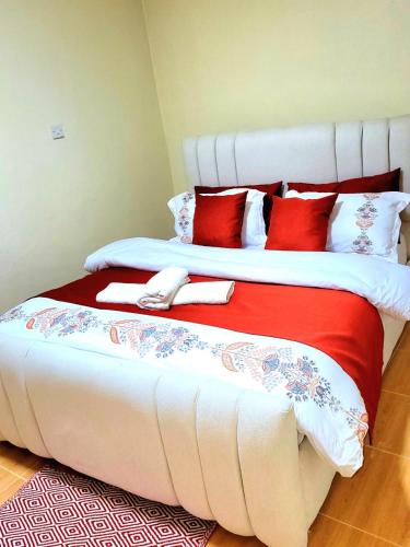 a bedroom with two beds with red and white pillows at HERIJ Staycation kitengela in Kitengela 