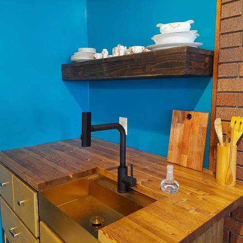 a sink in a kitchen with a blue wall at Cirque Stay in Lawrence