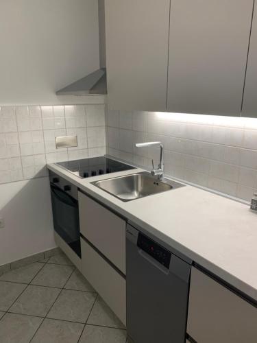 a white kitchen with a sink and a stove at Delux apartment Dora with a private parking in Rijeka
