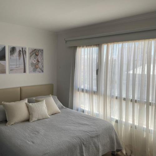 a bedroom with a bed and a large window at Aire de Mar II - Alojamientos Necochea in Necochea