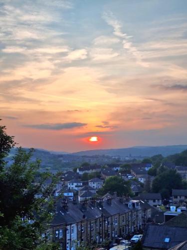 a sunset over a city with houses and buildings at Chestnut Lodge - a woodland escape near the city! in Bradford