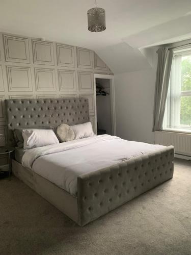 a large bed in a white bedroom with a large mattress at Chestnut Lodge - a woodland escape near the city! in Bradford