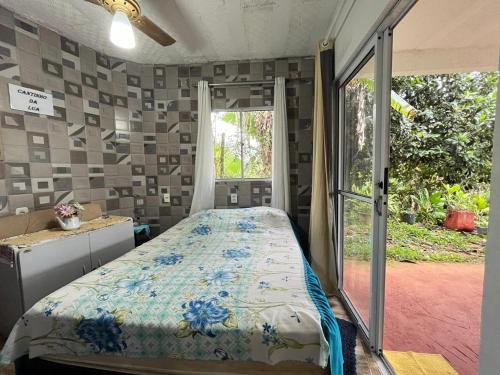 Un dormitorio con una cama y una puerta corrediza de vidrio. en CHÁCARA DOMINGOS MARTINS - SANTO GRAAL - Montanhas, Corredeiras, Piscina, Natureza e Paz, en Domingos Martins