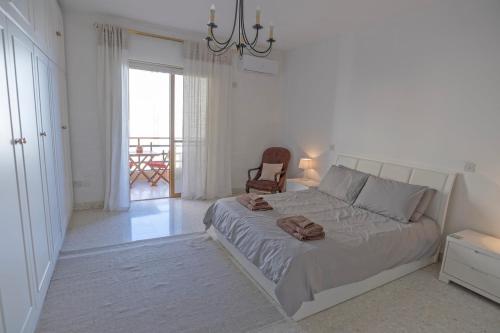 a white bedroom with a bed and a chair at Spacious 3-Bedroom Apartment with Balconies-Central Sliema in Sliema