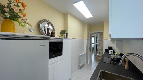 een keuken met een spoelbak en een koelkast bij Apartamento Playa de Gijon in Gijón