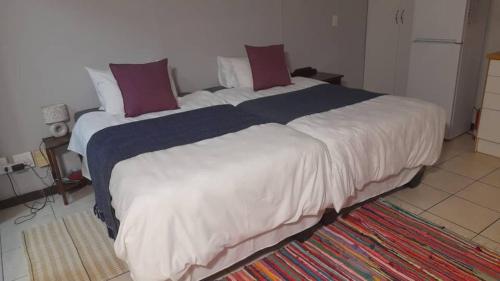 a bedroom with a large white bed with red pillows at Kelpmeeu Self- Catering and Car hire in Swakopmund