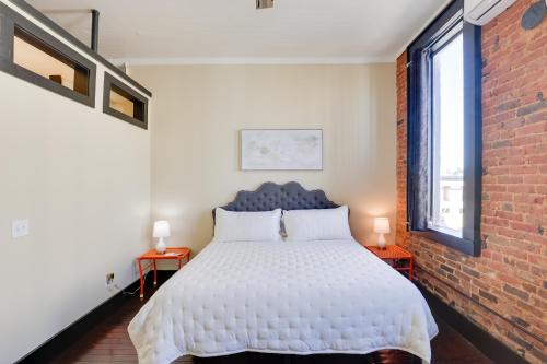 a bedroom with a white bed and a brick wall at Convenient Couples Retreat in Dtwn Marshall! in Marshall