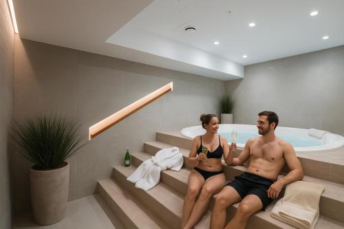 a man and a woman sitting on steps in a bath tub at Riverside Industrial Studios - SAUNA - GYM -air-conditioning-SPA-FITNESS in Wrocław