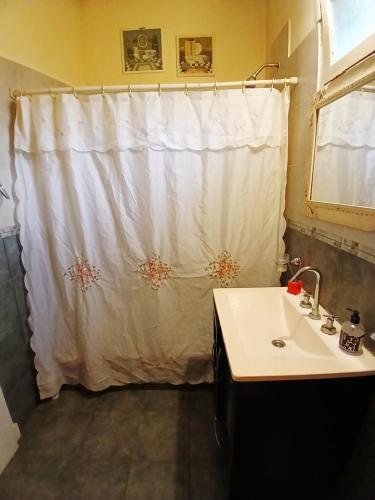 Un baño con una cortina de ducha blanca y un lavabo. en Alquilo casa en Villa Gesell por temporada, en Villa Gesell