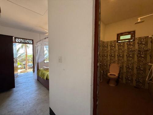 un bagno con wc e una stanza con un letto di kuda Bay Surf Hostel ad Arugam
