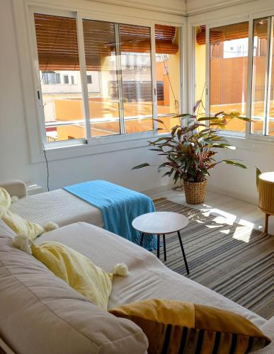 a room with two beds and a table and windows at Apartament Sant Feliu de Guixols in Sant Feliu de Guixols