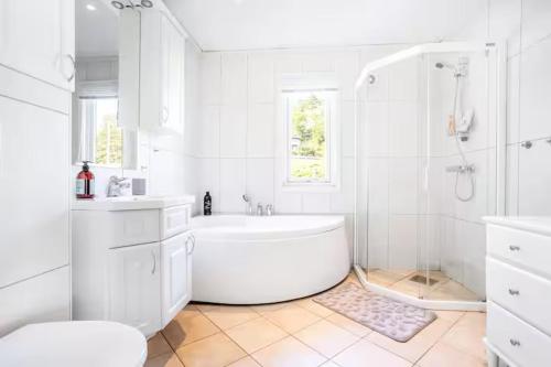 Un baño blanco con bañera y ducha. en Koselig leilighet strandnær opplevelse!, en Grimstad