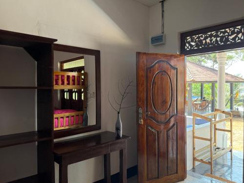 una camera con porta in legno e specchio di kuda Bay Surf Hostel ad Arugam