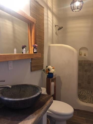 a bathroom with a stone sink and a toilet at Hotel Boutique casa la Malagueña in San Agustinillo