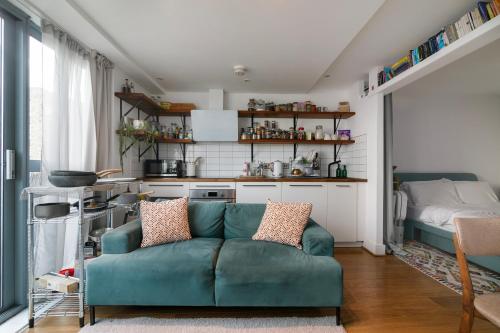 un salon avec un canapé vert et une cuisine dans l'établissement Charming Central Studio with Balcony in Birmingham, à Birmingham
