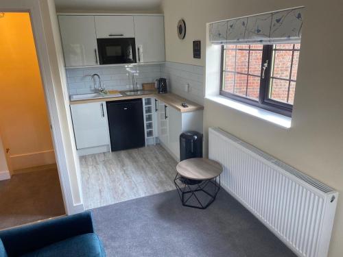 a small kitchen with a sink and a stool at Chimney View Annexe in Wootton
