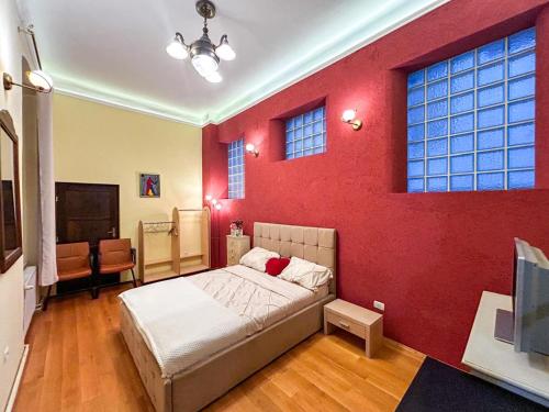 ein Schlafzimmer mit einer roten Wand mit einem Bett und einem Fernseher in der Unterkunft Ada Old Town 7 in Braşov