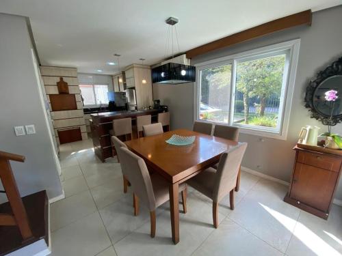 eine Küche und ein Esszimmer mit einem Holztisch und Stühlen in der Unterkunft Casa Tranquila - Condomínio Vila Verde Canela in Canela